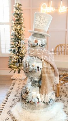 a snowman made out of disco balls on top of a rug next to a christmas tree