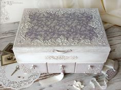 an ornately decorated white box sitting on top of a table next to scissors and lace