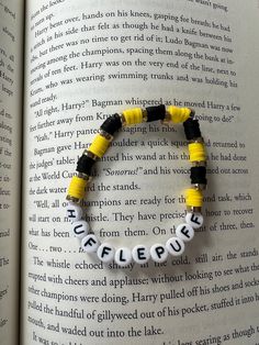 a yellow and black beaded bracelet sitting on top of an open book with words written in white letters