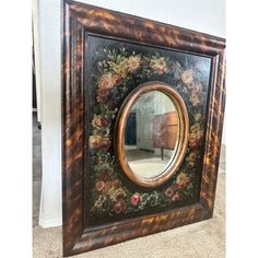 a mirror that is sitting on the floor in front of a wall with flowers painted on it