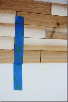 a piece of blue tape sitting on top of wooden planks next to a wall