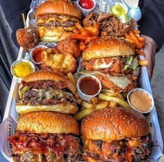 a tray filled with lots of different types of burgers and fries next to condiments