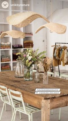 a wooden table topped with lots of vases filled with flowers next to a shelf