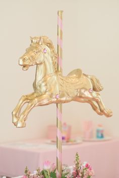 a gold carousel horse on top of a pink table