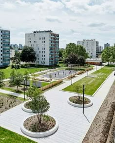 an aerial view of a park with trees and buildings in the background