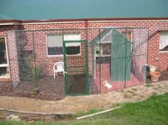 a small house with a chicken in it's cage next to a green roof