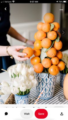 a woman is arranging oranges in small blue vases on a striped tablecloth