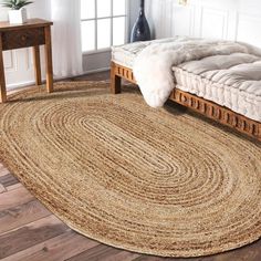 a large round rug in the middle of a room with a bed and side table