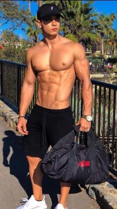 a shirtless man with no shirt holding a duffel bag and posing for the camera