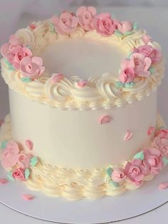 a three layer white cake with pink flowers on the top and bottom, sitting on a plate