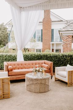 an outdoor seating area with wicker furniture and white drapes