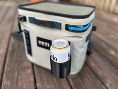 a cooler bag sitting on top of a wooden table next to a can of beer