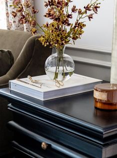 a vase with flowers sitting on top of a table next to a book and candle