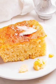 a piece of cake on a white plate with some sugar and lemons next to it