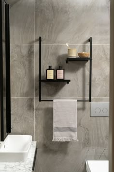 a white toilet sitting next to a sink under a bathroom mirror in a room with gray walls