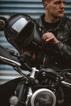 a man sitting on top of a motorcycle with a helmet on it's back