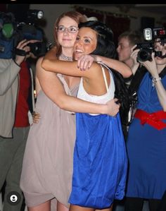 two women hugging each other in front of cameras