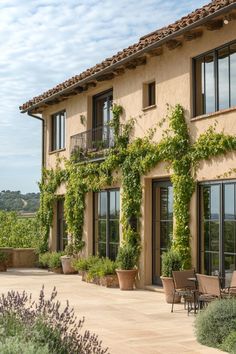 an outdoor patio with tables and chairs next to a large building covered in green vines