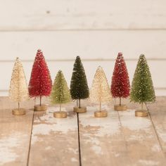 small christmas trees are lined up on a wooden table