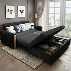 a black couch with drawers underneath it in a living room next to a large window