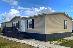 a mobile home sits in the grass with steps leading up to it