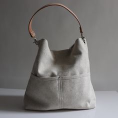 a white purse sitting on top of a table next to a gray wall with a brown leather handle