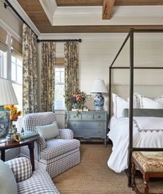 a bed room with a neatly made bed next to two chairs and a table in front of a window