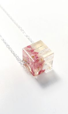 a pink flowered glass cube necklace on a silver chain