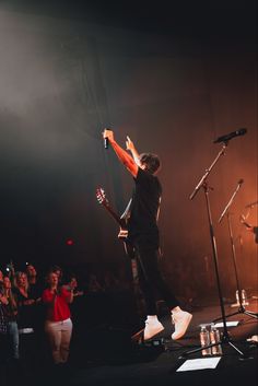 a man standing on top of a stage with his arms in the air and holding a microphone