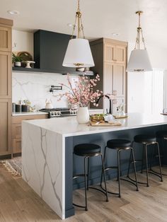 a kitchen with an island and bar stools in it, next to the counter