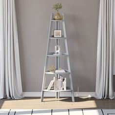 a white shelf with books on it in front of a gray wall and window curtains