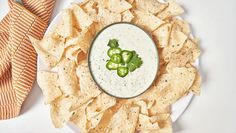 a white plate topped with tortilla chips next to a bowl of guacamole