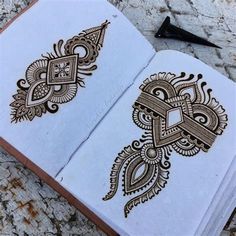 an open book with intricate designs on the pages and inside is sitting on a stone surface