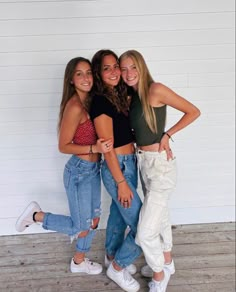 three girls posing for the camera with their arms around each other and one girl wearing ripped jeans