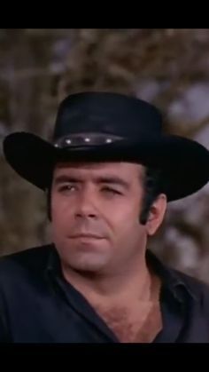 a man wearing a black cowboy hat looking at the camera