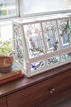 a stained glass box sitting on top of a dresser next to a potted plant