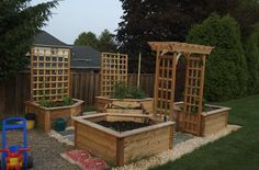 an outdoor garden area with wooden planters and plants in them, including trelliss