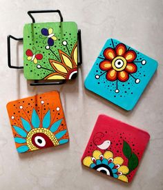 four brightly painted coasters sitting on top of a white table next to each other