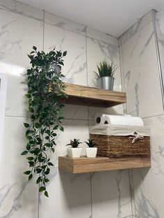 two wooden shelves with plants and towels on them in a bathroom area that has white tile walls