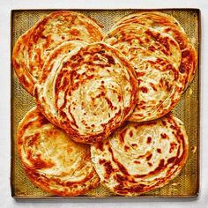 several flat breads are arranged on a baking tray