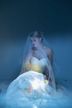 a woman in a wedding dress sitting on the floor with her hands under her face