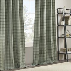 the curtains in this room are green and white plaid fabric, with a window behind them