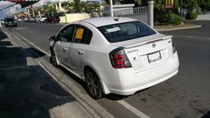 a white car is parked on the side of the road