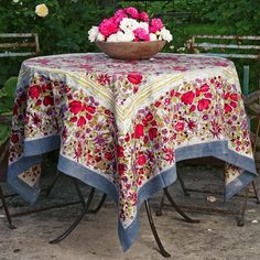 a bowl with flowers is on top of a table in the middle of some chairs