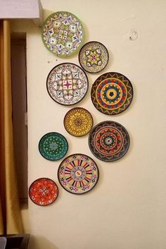 there are many plates hanging on the wall in this room, and one is decorated with colorful designs