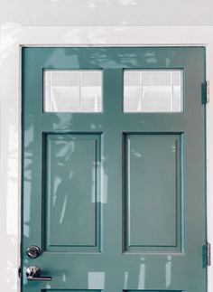 a green front door with two windows on the top and bottom half, in white trim