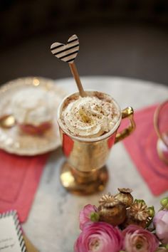 an image of a drink in a gold cup on a table with pink napkins