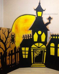 an art project with black and yellow paper cutouts on the wall, depicting a house at night