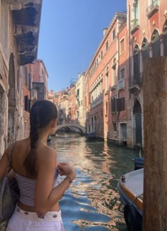 a woman standing on the side of a boat looking at buildings and water in venice, italy