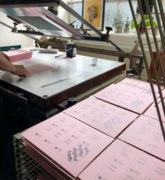 a person standing in front of a stack of pink boxes on top of a table